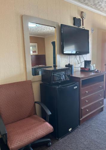 a room with a chair and a television and a dresser at Deavers motel in Grove Hill