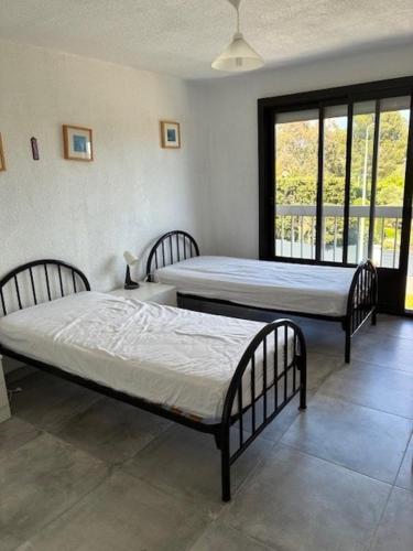 deux lits dans une chambre avec deux fenêtres dans l'établissement appartement bord de mer, Esterel, à Agay
