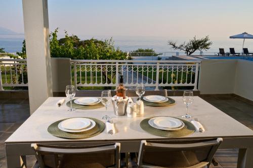 a table with plates and wine glasses on a balcony at Grand Villa Maronia in Platanitis Rodopis