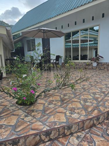 a stone patio with flowers in front of a building at Loversnest Self Catering in Anse aux Pins
