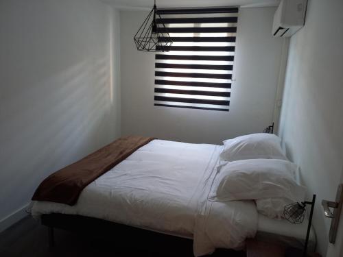 une chambre avec un lit avec des draps blancs et une fenêtre dans l'établissement 70m2 appartement Central, au Grau-du-Roi