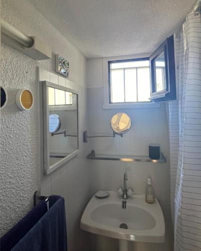 une salle de bain avec un lavabo, un miroir et une fenêtre dans l'établissement studio à 400m de la plage de la Corniche, à Sète