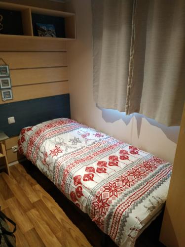 Ce lit se trouve dans un dortoir doté d'une couette rouge et blanche. dans l'établissement mobil home chez ANIK & ALAIN, à La Roque-dʼAnthéron