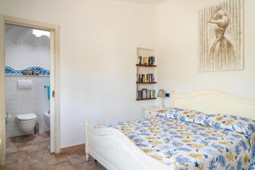 a white bedroom with a bed and a bathroom at Villa Aratza in Orosei