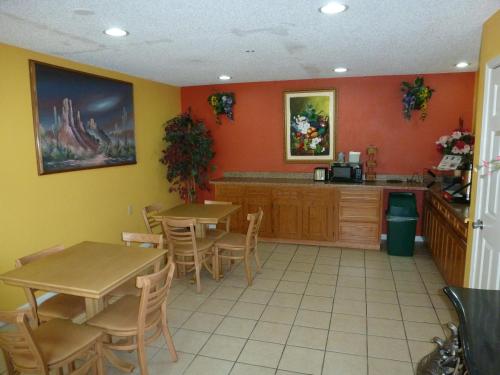 un restaurante con 2 mesas y una cocina con paredes de color naranja en Redwood Inn - White Hall, en White Hall