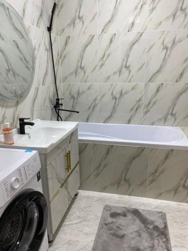 a bathroom with a sink and a washing machine at Апартамент Рахима Плаза2 in Shymkent