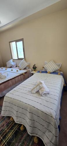 two twin beds in a room with a window at Dar Tamatert in Tamatert