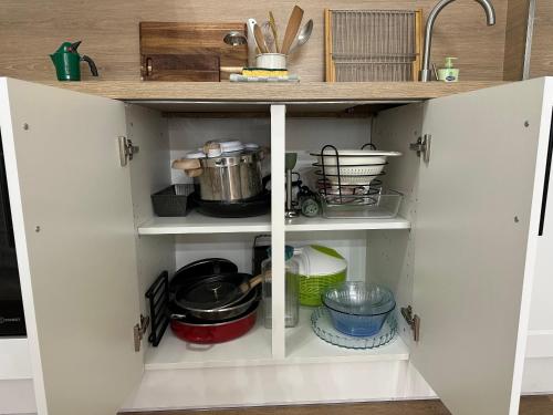 a kitchen cabinet filled with dishes and utensils at Aroma Cite Vauban in Briançon