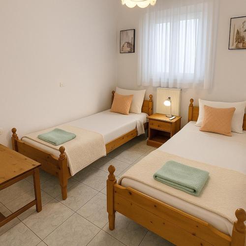 a room with two beds and a table with a table at Alexia Apartments & Studios in Kremasti
