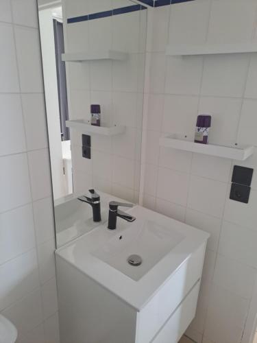 une salle de bain blanche avec un lavabo et un miroir dans l'établissement STUDIO CLIMATISE box 5 G Résidence Odalys Saint Loup, piscine ,parking privé et superette 25, au Cap d'Agde