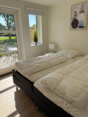 two beds in a bedroom with a window at Bøtø strand ferielejlighed 3 in Marielyst