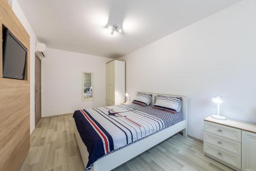 a white bedroom with a bed and a dresser at Apartment Caricia complex Carpe Diem Balchik - sea view & free parking in Balchik