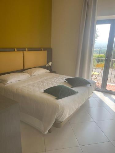a large bed in a bedroom with a large window at Tuscasì Aparthotel in Sovicille