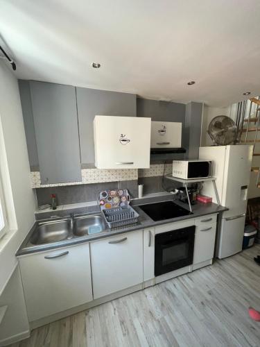 une cuisine avec un évier et une cuisinière four supérieur dans l'établissement Appartement dans le village à port la nouvelle, à Port-la-Nouvelle