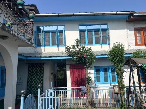 ein weißes Haus mit blauen Fenstern und einer Veranda in der Unterkunft Mir heritage in Srinagar