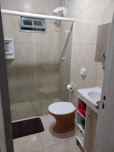 a bathroom with a shower and a toilet and a sink at Meu lar na praia in Jaguaruna