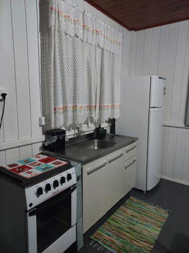 a kitchen with a stove and a sink and a refrigerator at Meu lar na praia in Jaguaruna