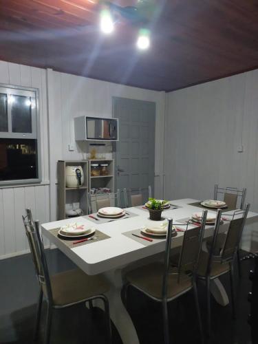 a dining room with a table and chairs and a kitchen at Meu lar na praia in Jaguaruna