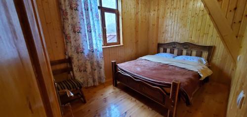 a bed in a wooden room with a window at GuestHouse Ellie- Elisabeth in Adishi