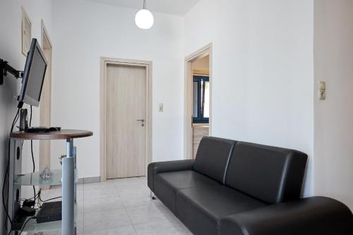 a living room with a black couch and a desk at Thea Apartment 3 in Emporeios