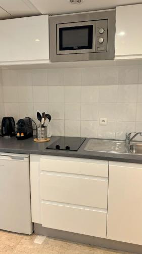 une cuisine blanche avec un évier et un micro-ondes dans l'établissement Studio 4 Carré d'Or, à Nice