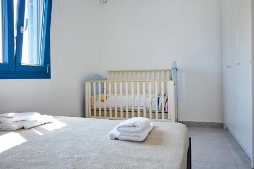 a bedroom with a crib and two towels on a bed at Thea Apartment 3 in Emporeios