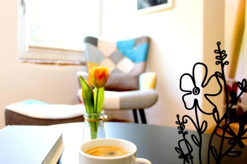 a table with a cup of coffee and a vase with a flower at Ferienhaus Laufen in Laufen