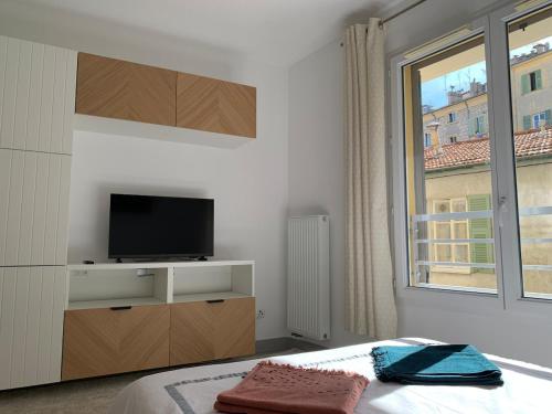 une chambre avec un lit, une télévision et une fenêtre dans l'établissement Joli studio, quartier du port, à Nice