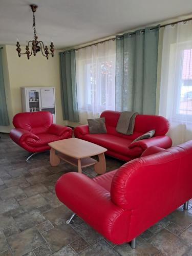 a living room with red couches and a table at Apartament nad jeziorem in Małe Swornegacie