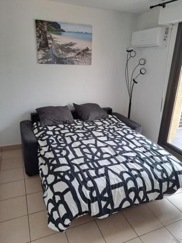 une chambre avec un lit avec une couette noire et blanche dans l'établissement Studio Climatisé Résidence Odalys nouvelle box 5 G ,Saint Loup,piscine ,parking privé et superette, au Cap d'Agde