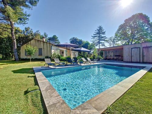 une piscine avec chaises et parasols dans une cour dans l'établissement Villa tout équipée - Piscine & pool house - CLIM, à Uzès