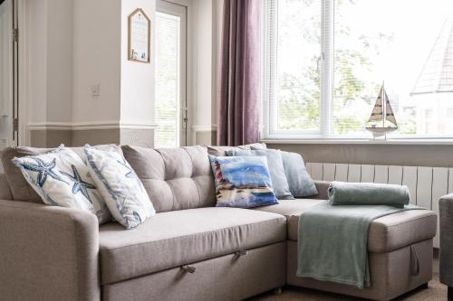 a couch in a living room with pillows on it at Sandy Seashells in Bournemouth