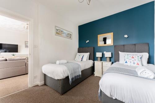 a bedroom with two beds and a blue wall at Sandy Seashells in Bournemouth