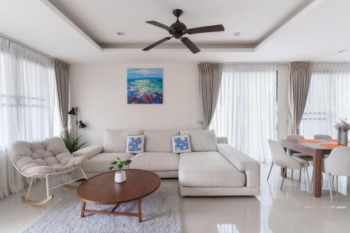 a living room with a couch and a ceiling fan at Friendly Townhouse Laguna Park in Thalang