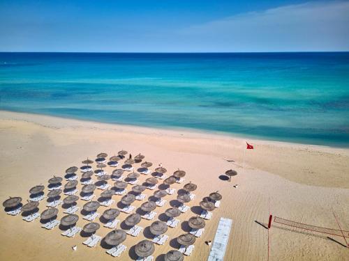 a group of umbrellas and chairs on a beach at Nahrawess Resort & Thalasso in Hammamet