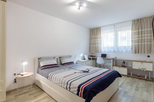 a white bedroom with a bed and a desk at Apartment Caricia complex Carpe Diem Balchik in Balchik