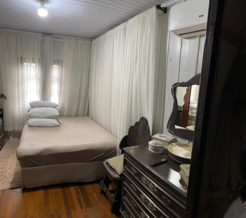 a small bedroom with a bed and a mirror at Casa Vovó Slaviero in Pomerode
