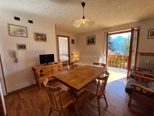 comedor con mesa de madera y TV en Appartamento Salice 2000 - G, en Sauze d'Oulx