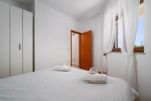 a white bedroom with a bed and a window at Serene Summer Oasis - Pool, Jacuzzi, Sauna, Sea View - Lara in Drenje