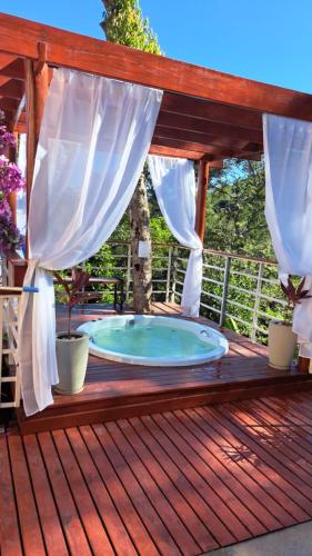 a hot tub on a wooden deck with curtains at Casa, hidro, piscina, aconchego e uma linda vista! in Mairiporã