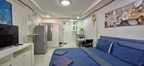 a bedroom with a blue bed and a kitchen at Rawai Condotel 3 in Rawai Beach