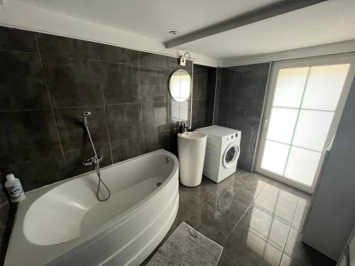 une salle de bain avec baignoire et machine à laver dans l'établissement La Suite Pitot - 50m de Arc de Triomphe, à Montpellier