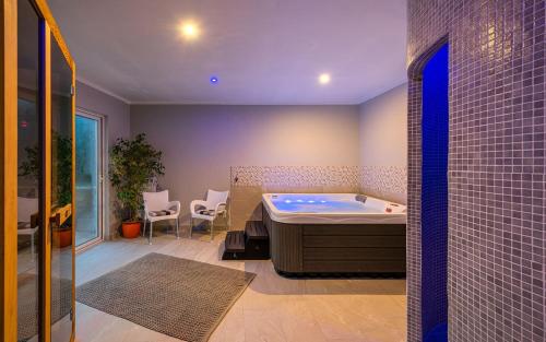 a bathroom with a tub and a table and chairs at Serene Summer Oasis - Pool, Jacuzzi, Sauna, Sea View - Lara in Drenje