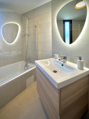 une salle de bain avec un lavabo, une baignoire et un miroir dans l'établissement Théoule - Refait à neuf - 6 personnes - Parking - Clim, à Théoule-sur-Mer