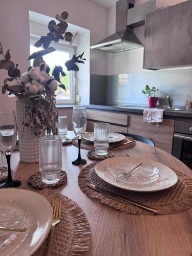 a wooden table with plates and wine glasses on it at Rezidenca Vista Lux in Ptuj