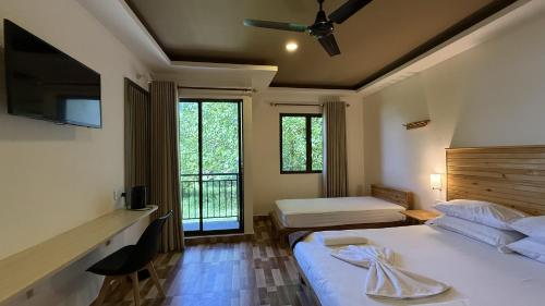 a bedroom with two beds and a tv and windows at Belmar Beach in Bodufolhudhoo