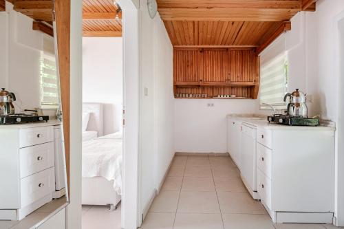 una cucina con mobili bianchi e soffitto in legno di Marmara Yali Evi a Isola di Marmara