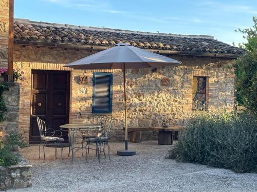 a table and chairs with an umbrella in front of a building at Radius Horse Ranch B&B in Massa Martana