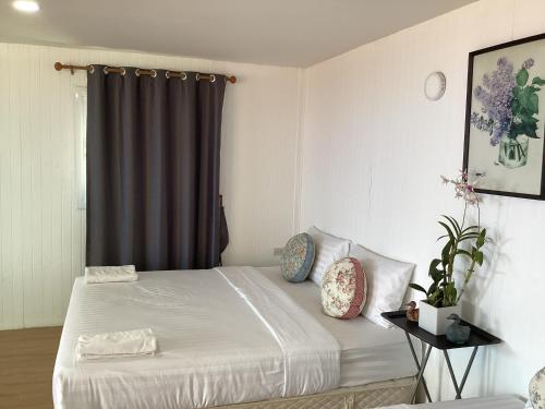 una camera da letto con un letto con lenzuola bianche e una finestra di MumTarn Homestay มุมธาร โฮมสเตย์ a Ban Nong Sarai (1)