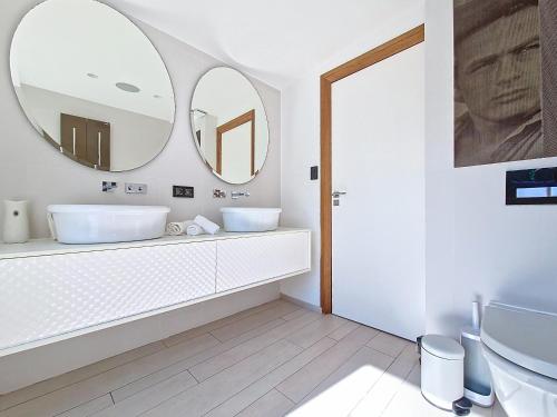 une salle de bain avec deux lavabos et deux miroirs dans l'établissement Villa Architecte Détente Piscine Privée Cinéma, à Sète